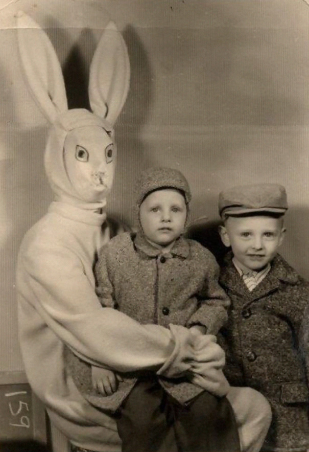 A imagem mostra um coelhinho da Pascoa em tamanho humano envolvendo uma criança nos braços