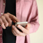 Unrecognizable man holding smartphone and touching screen